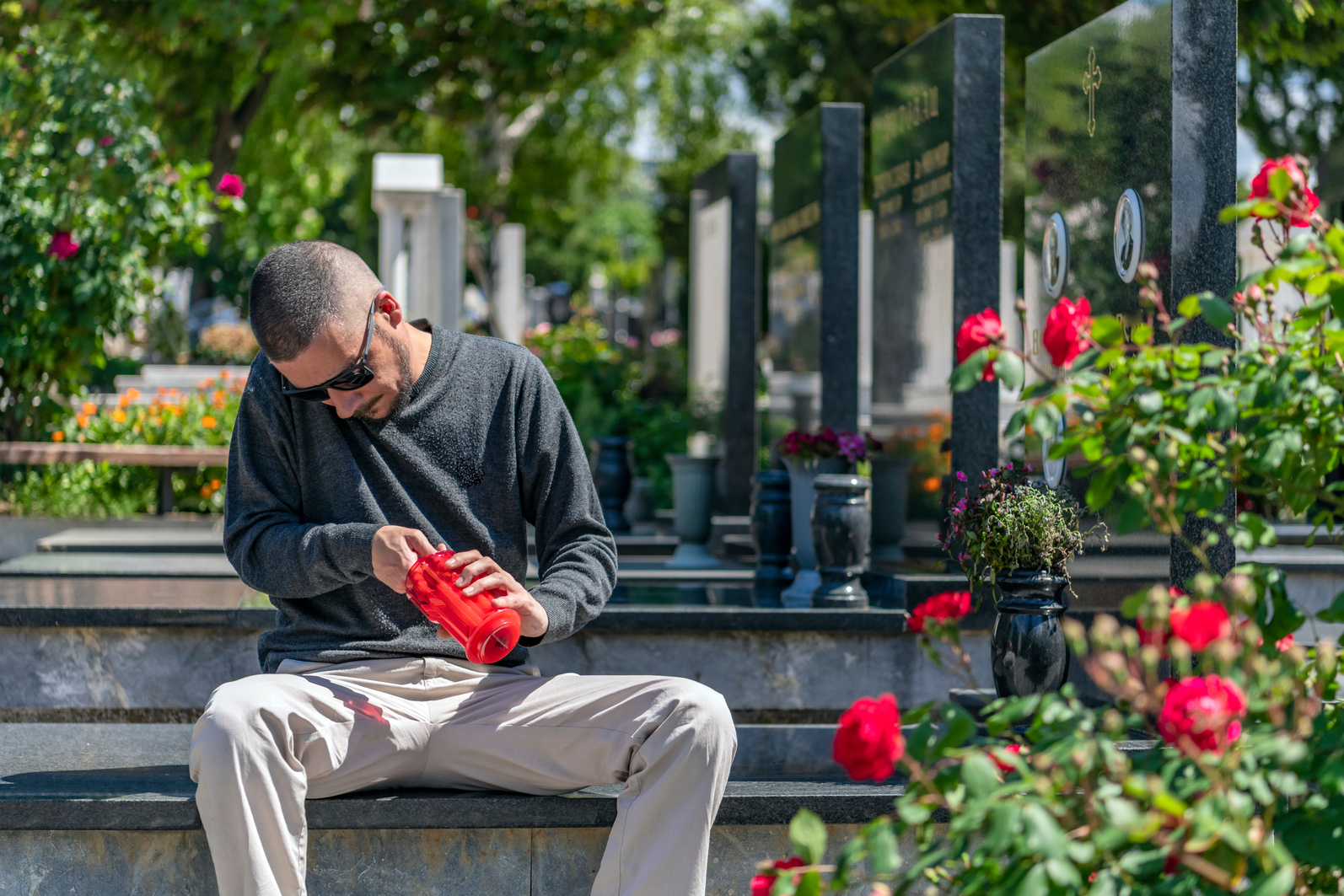 Man Sitting At Grave Sites with Red Candle